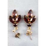 A yellow metal pair of drop earrings each set with faceted cut red paste stones.