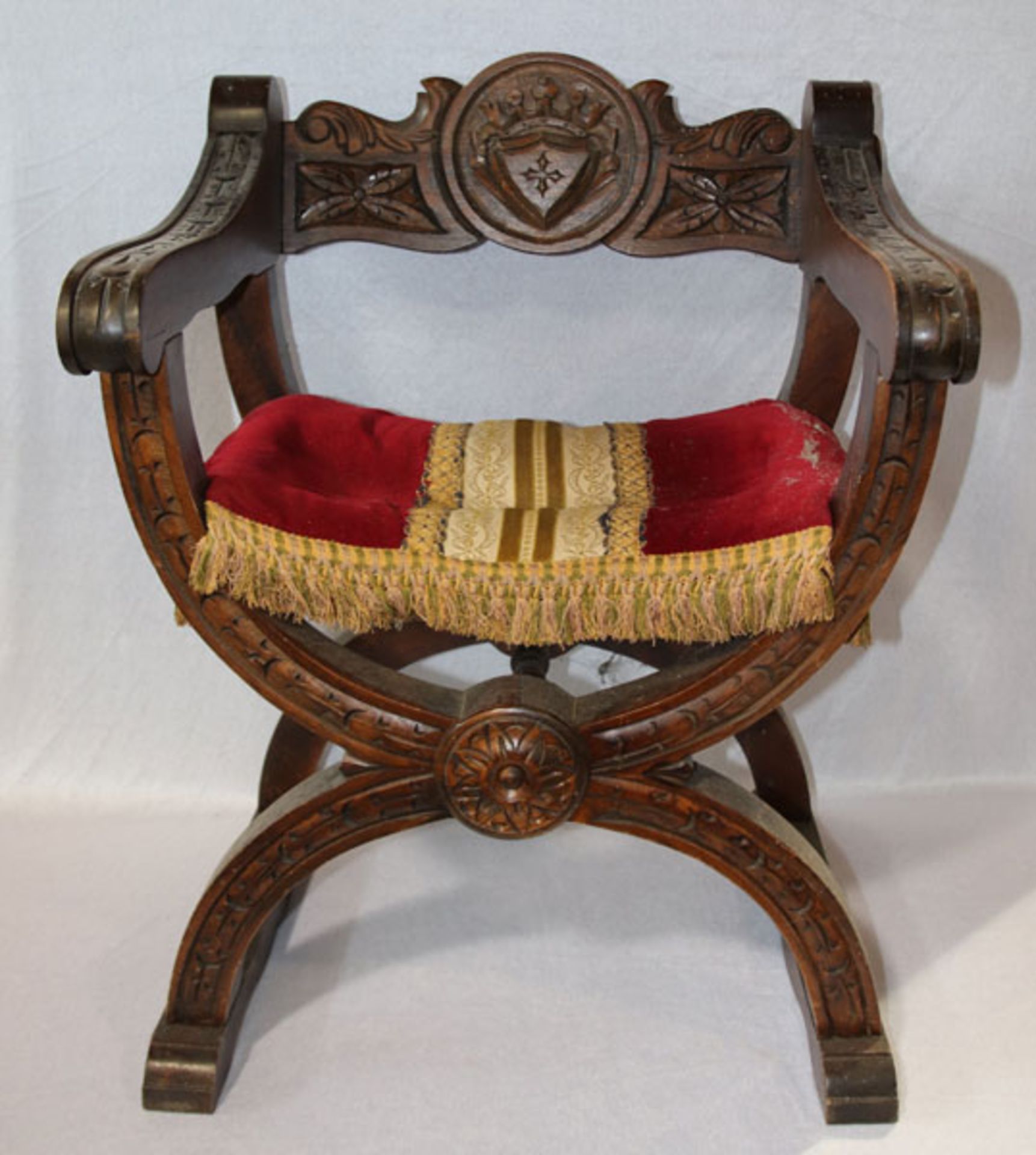 Spanischer Kreuzbeinstuhl, Sitz gepolstert und rot bezogen, teils beschnitzt, H 73 cm, B 62 cm, T 54