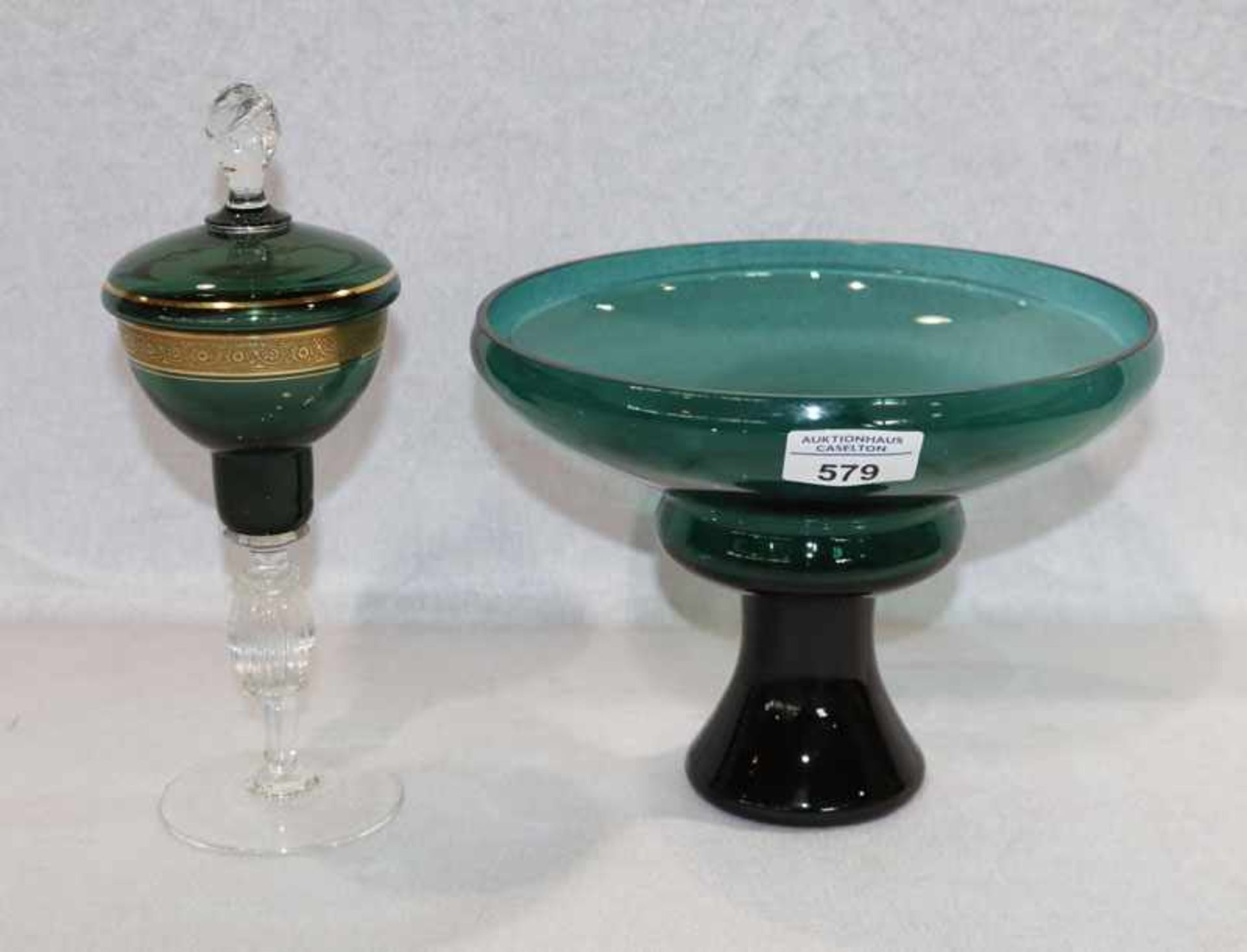 Glas Deckeldose, grün mit Golddekor auf klarem Fuß, H 25,5 cm, und grüne Glas-Fußschale, H 17 cm,