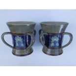 A pair of Royal Doulton four-handled stoneware vases, the waisted sides with a dark blue frieze