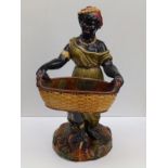 A 19thC majolica female blackamoor figure, carrying a basket, 20" high.