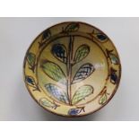 A 19thC slipware bowl decorated with a leafy stem, 12" diameter.