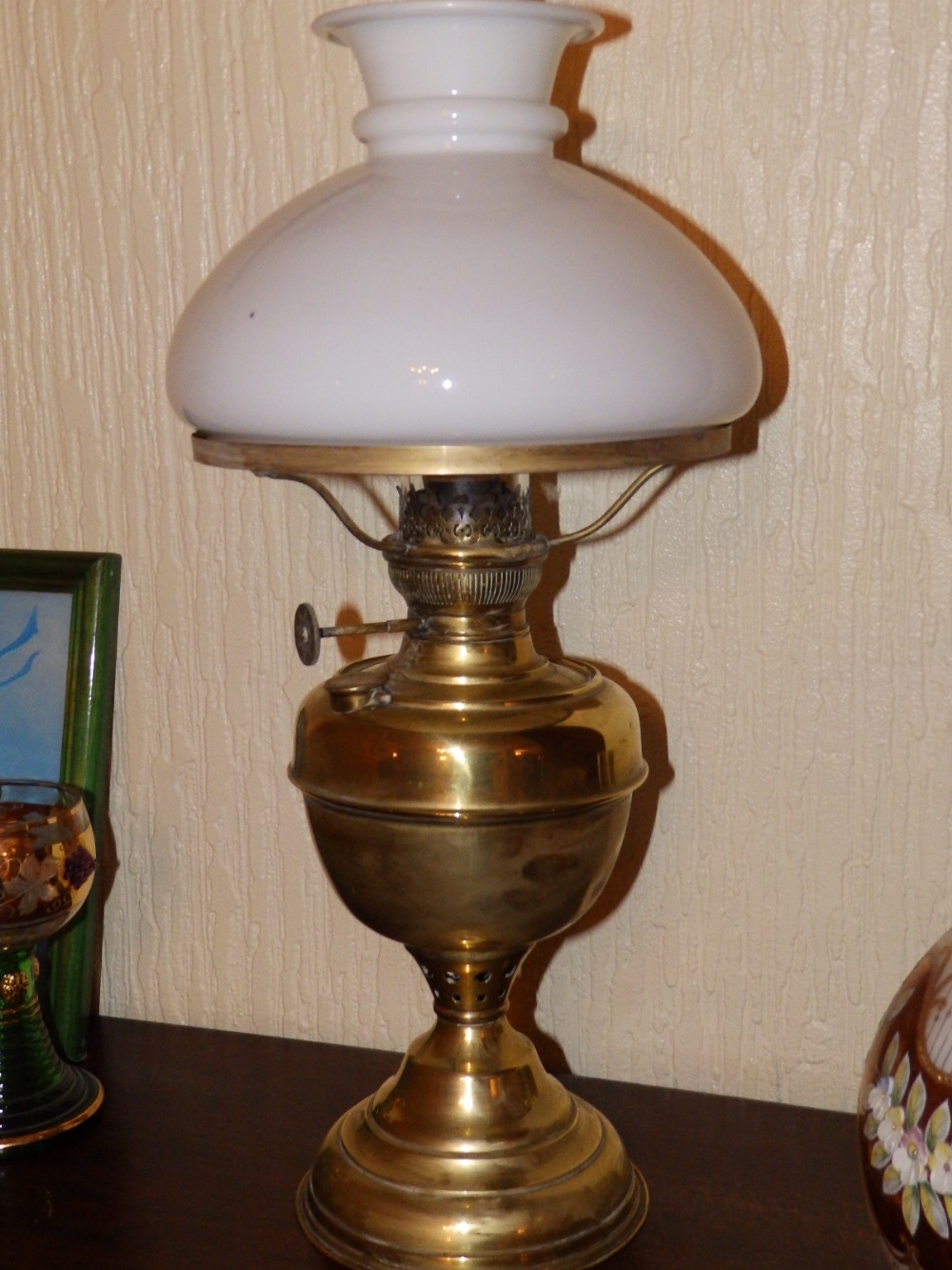 A brass oil lamp with white glass shade.