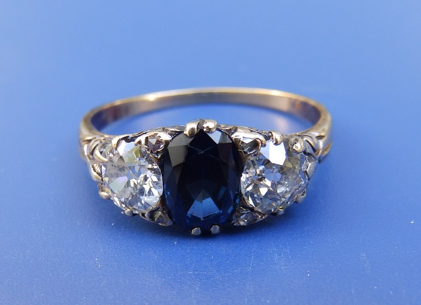 A three stone sapphire & diamond ring, the cushion cut sapphire flanked by two old cut diamonds