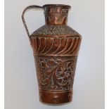 An Arts & Crafts embossed copper jug, the shoulders decorated leafy trefoils, the body having a