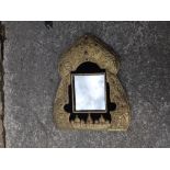 An Indo-Persian gilt metal wall mirror of mihrab arch shape embossed architectural details, plants