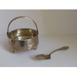 A Russian white metal swing-handled sugar bowl and a spoon. (2)
