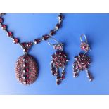 A Victorian garnet coloured metal necklace and a pair of earrings (each missing a drop) together