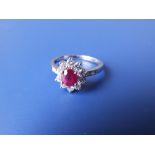 An oval ruby & diamond cluster ring in 18K white metal to match the previous lot. Finger size Q/R.