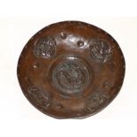 A bronze patinated embossed copper bowl, decorated with four grotesque/caricature masks about a