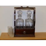 A reproduction two bottle tantalus and a pair of tumblers engraved with galleon pattern.