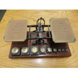 A set of Mordan & Co. letter scales with weights on mahogany base.