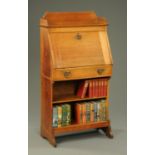 An Arts & Crafts oak students bureau, with shelf, fall front and open shelves beneath. Width 69 cm.