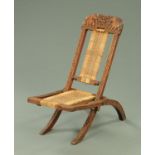 An Eastern carved wooden folding chair, carved with elephants and scrollwork. Width 37.