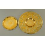 An Arts & Crafts embossed brass circular tray, diameter 46 cm, and another.