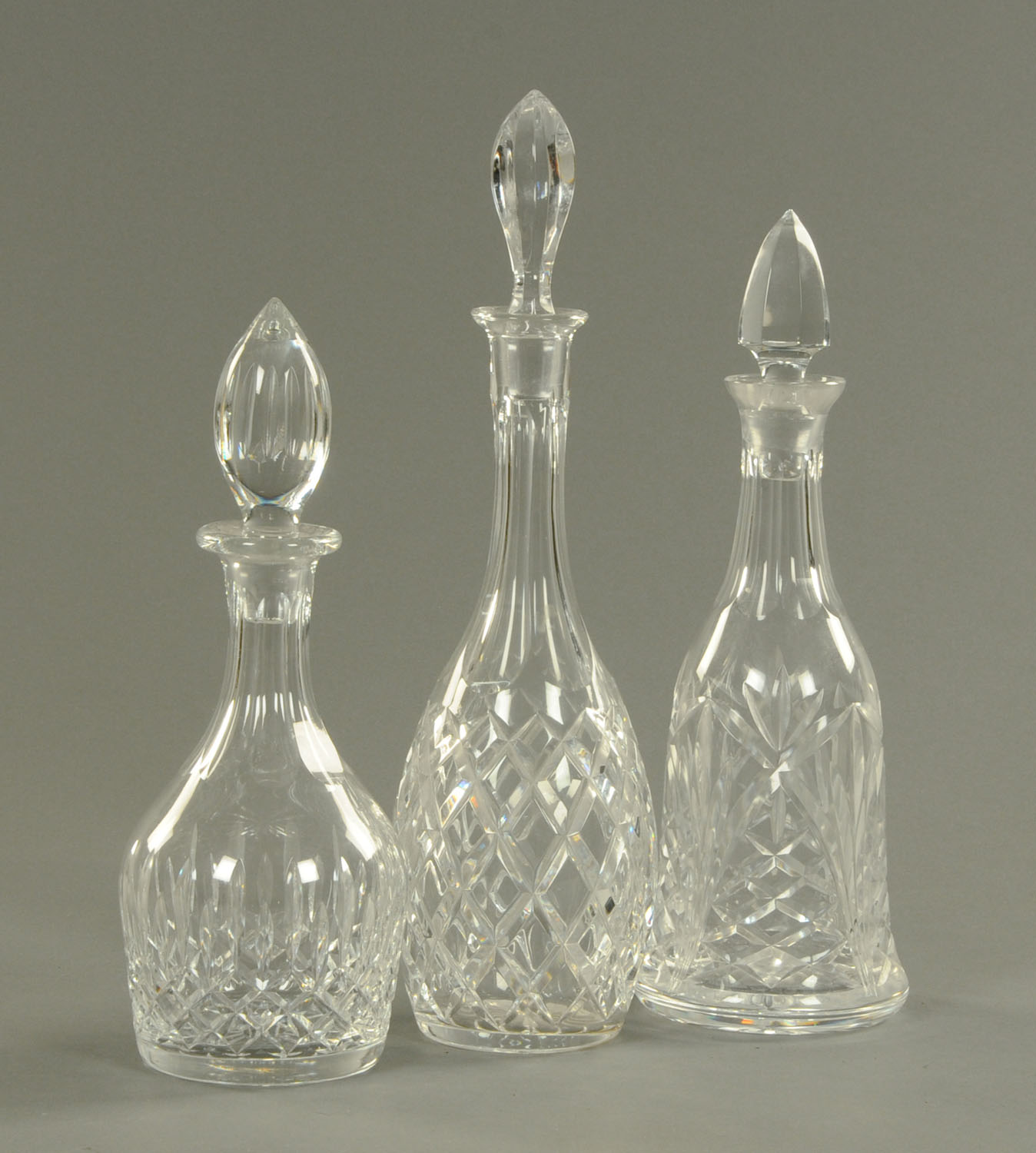 Three cut glass decanters, each with stopper. Tallest 40 cm.