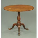 A George III oak tripod table, with snap action, turned column and three downswept legs.