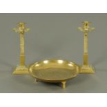 A Chinese brass circular dish, diameter 23 cm, and a pair of Eastern influence brass candlesticks,