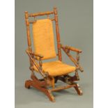 A late Victorian child's American rocking chair, with upholstered back and seat.