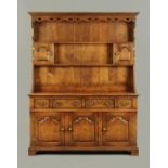 A reproduction oak dresser, with moulded dentil cornice above a series of shelves and cupboards,