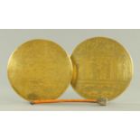 Two Egyptian brass gongs, with one beater. Largest diameter 27 cm.