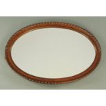 A mahogany framed mirror, oval, with bevelled glass and lobed edge. Width 85 cm.