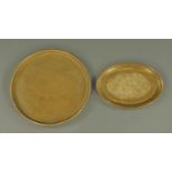 An Eastern brass tray, circular, and an oval platter. Tray diameter 48 cm.
