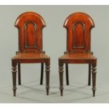 A pair of Victorian mahogany hall chairs, with shaped backs, solid seats and turned front legs.