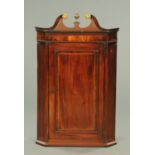 An early 19th century mahogany hanging corner cupboard,