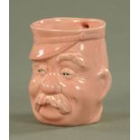 After Bruce Bairnsfather, a pottery moulded mug of "Old Bill", in pink glaze. Height 11.5 cm.