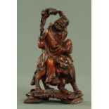 A Japanese carved stained boxwood figure of a deity seated on a Shi Shi, Meiji period,