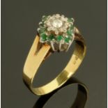 An 18 ct gold dress ring, set with a central diamond framed by emeralds, size O, 4.1 grams gross.