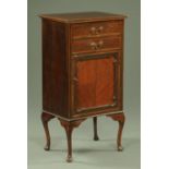 An Edwardian inlaid mahogany music cabinet, with two drawers above a cupboard door,