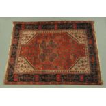 An Eastern fringed rug, principal colours red, black, blue and beige,