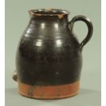 A large 19th century glazed pottery jug, with loop handle and front carrying support. Height 35 cm.