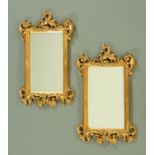 A pair of composition gilt framed mirrors, with rococo style mouldings and bevelled mirror glass,