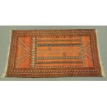 An Eastern fringed rug, principle colours red, blue and beige,