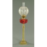 A 19th century brass column oil lamp, with cranberry reservoir and etched glass shade.