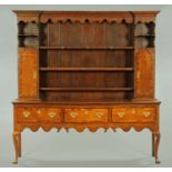 A George III oak dresser, the rack with moulded cornice above a series of shelves and cupboards,