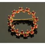 A 9 ct gold circular brooch, set with garnets. Diameter 23 mm.