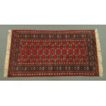 An Indian Bokhara fringed rug, with centre rectangular panel and multiple line border,