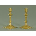 A pair of petal base brass candlesticks, early 18th century, with knopped stem above a wide base.