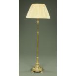 A late 19th century brass lamp standard, with circular moulded base raised on four feet, adjustable,