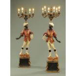 A pair of painted composition Blackamoor candelabra lamp standards, each raised on a shaped base,