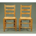 A pair of Cotswold School rush seated occasional chairs, with bar backs, turned legs and stretchers.