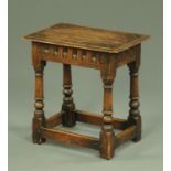 An oak joint stool, with carved frieze and turned legs united by low stretchers. Width 45.5 cm.