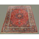 A large Iranian carpet, with fringed ends and repeating foliate pattern, principle colours red,
