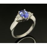 An 18 ct white gold ring, with central tanzanite and diamond shoulders, total weight +/- 1.