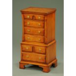 A Reprodux miniature walnut tallboy, the top half with two short and three long graduated drawers,