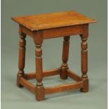 An oak joint stool, rectangular, raised on turned legs united by low stretchers. Width 45 cm.